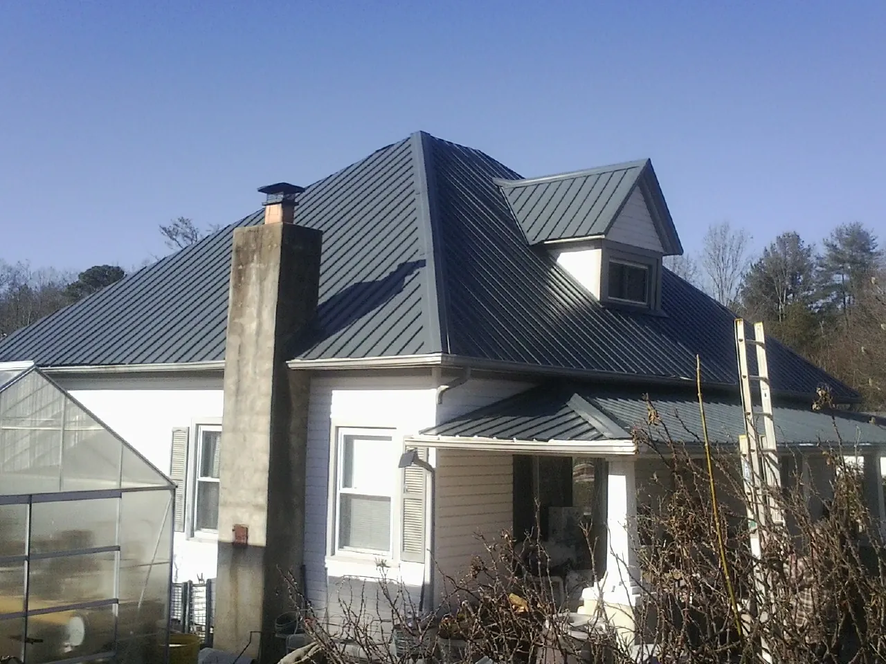 Dark blue standing seam metal roof on a white farmhouse with dormer — Slate & Tile Roof Repair by Roofing Brothers in Mill Valley