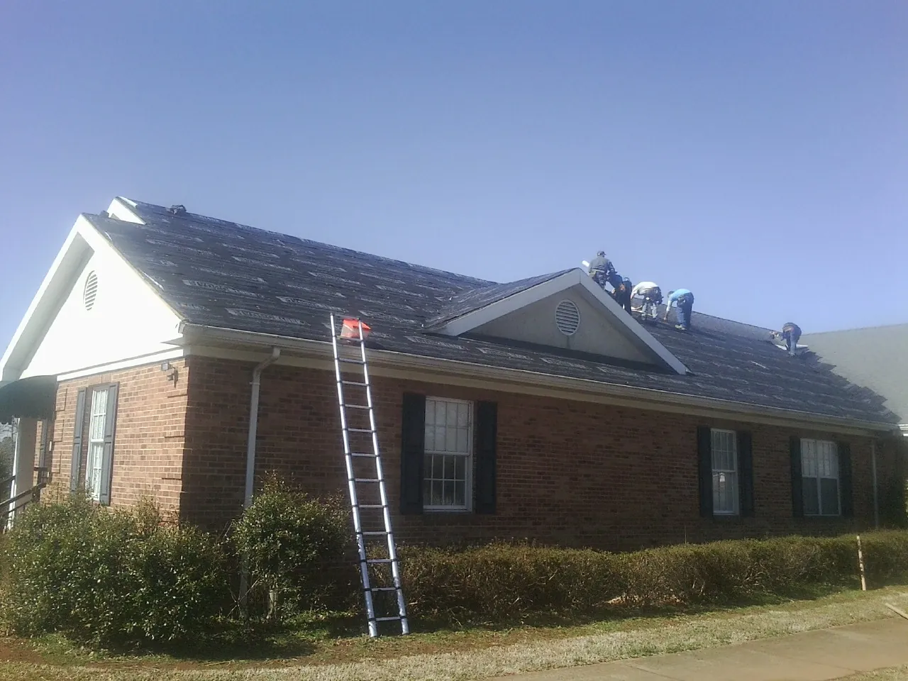 Crew tearing shingles off a brick ranch roof with a ladder set — Metal Roof Repair work by our crew in Mill Valley