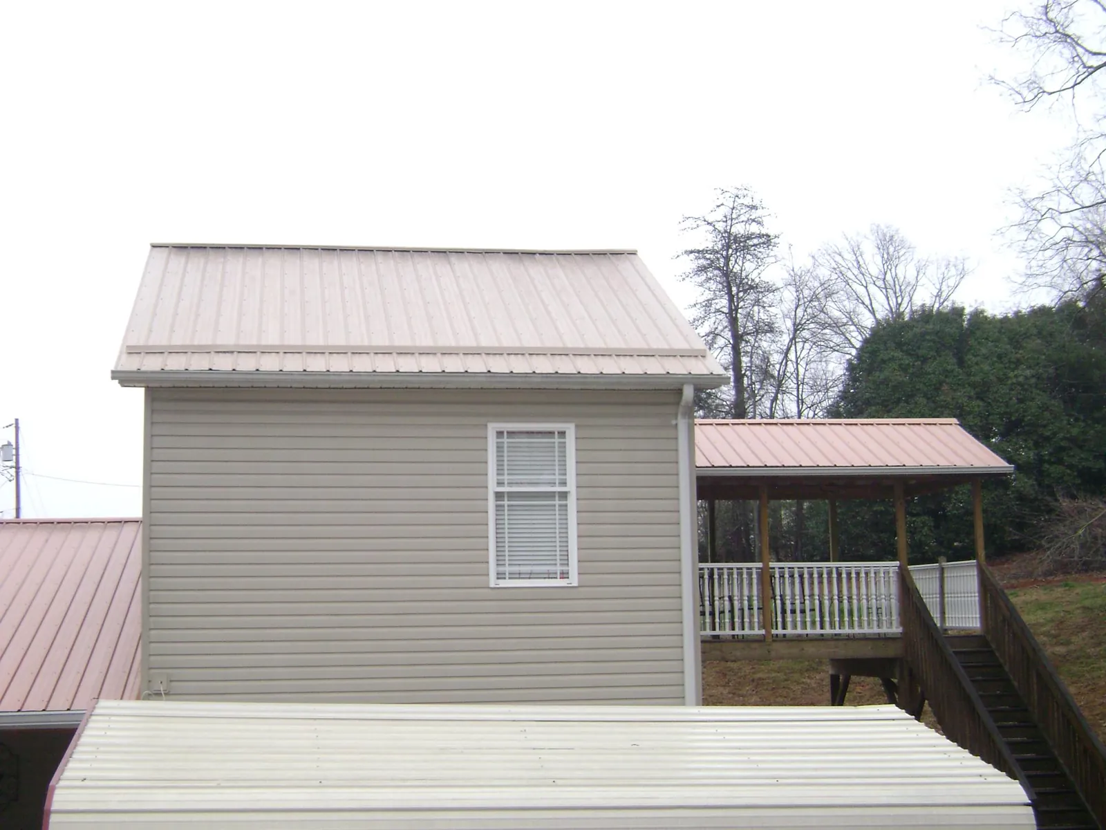 Tan metal roofs on a two story addition and attached porch, from a Roof Replacement job in Mill Valley
